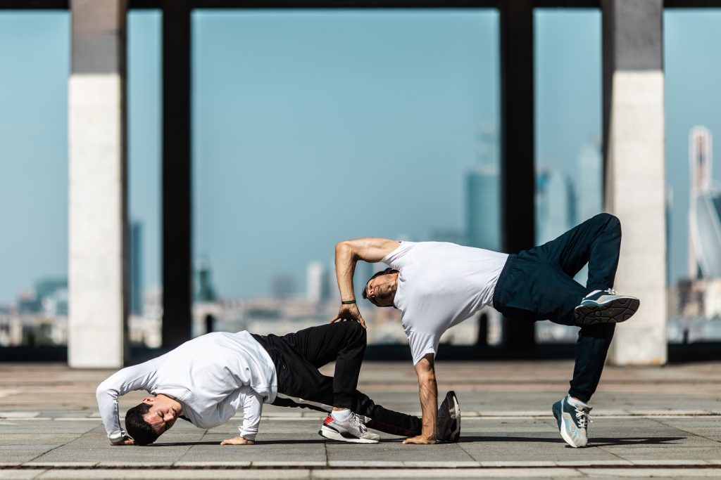 Entreprises Two men performing breakdance moves on a city street under a clear sky.