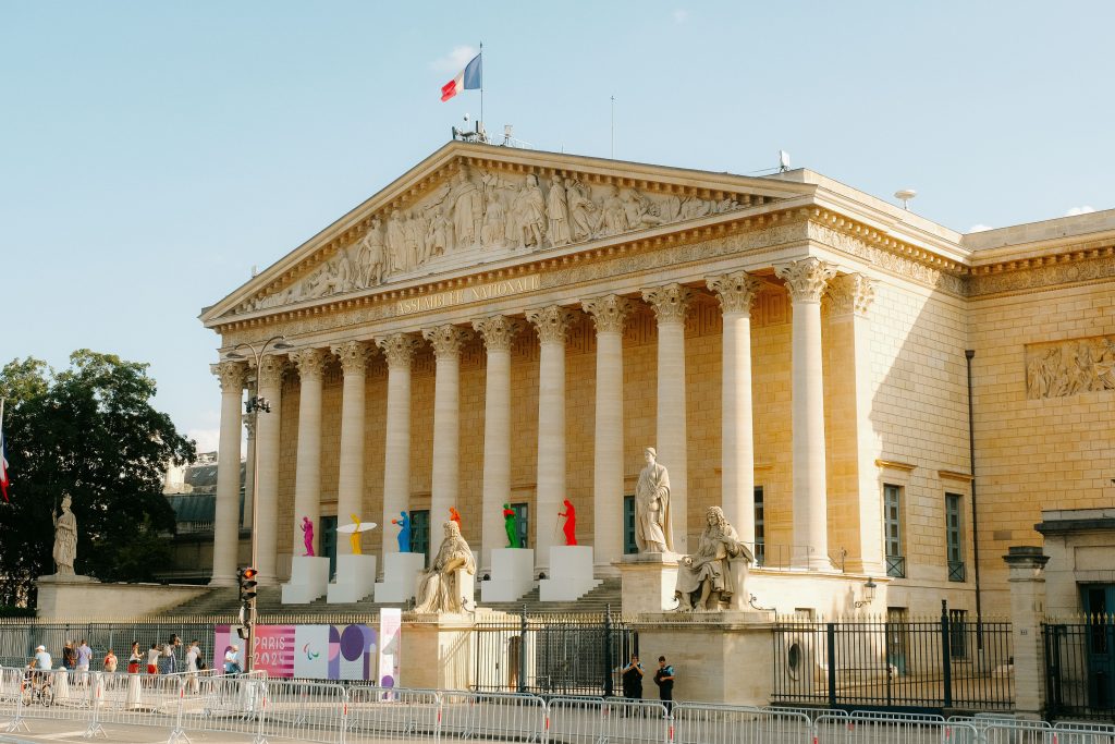 Bilan de compétences Front view of the Palais Bourbon in Paris, featuring statues and French flag.