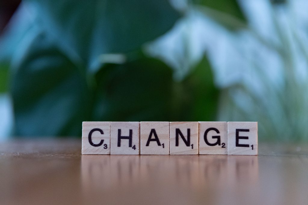 Check-up dirigeants Scrabble tiles spelling 'CHANGE' on a wooden surface with a blurred green background.